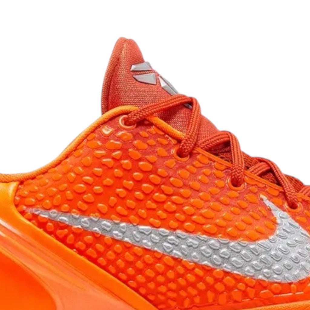 Close-up of an orange sports shoe with a white swoosh logo on a white background