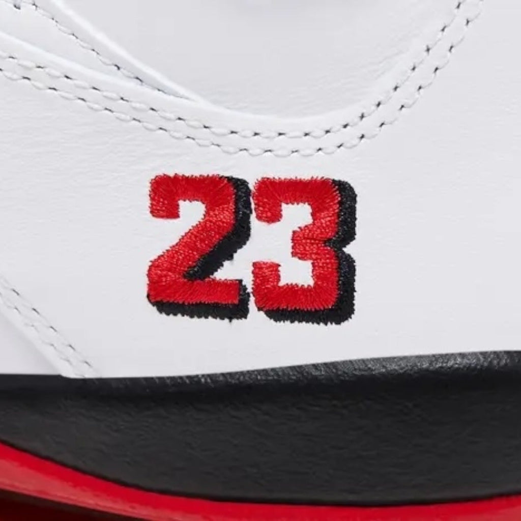 Close-up of a white sneaker with red and black '23' embroidery on a white background