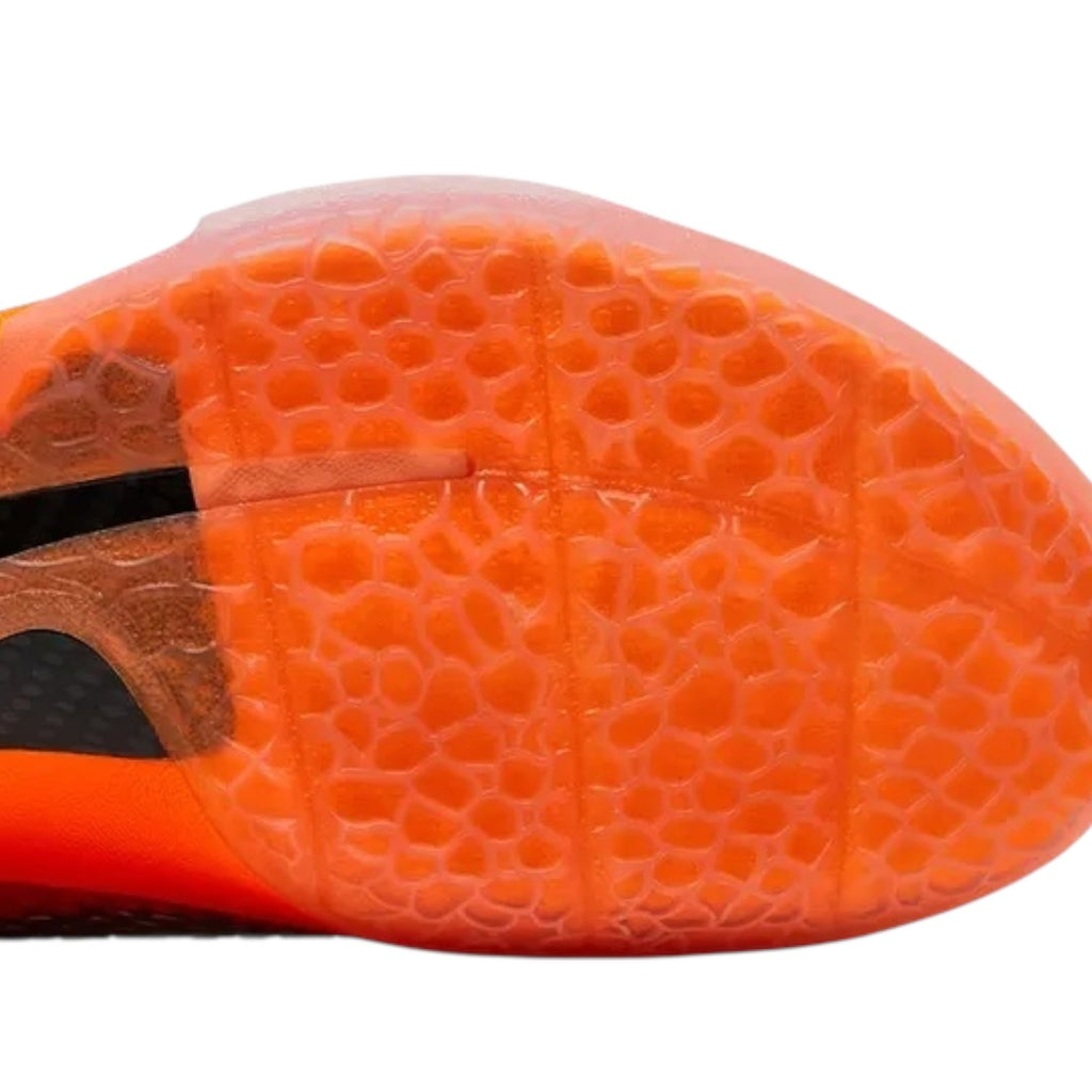 Close-up of an orange sports shoe sole with a textured pattern on a white background