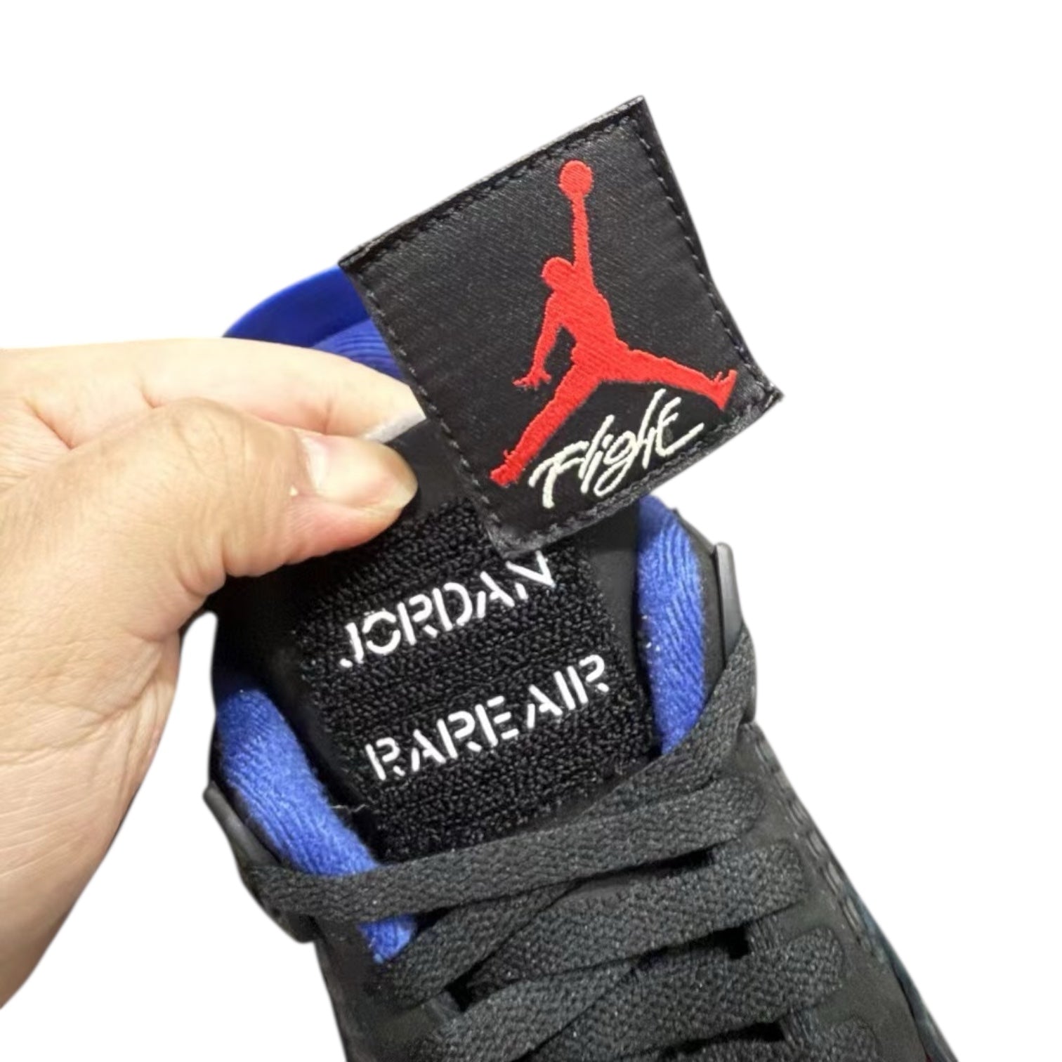 Hand holding a sneaker with a Jordan Rare Air label and red logo on a white background